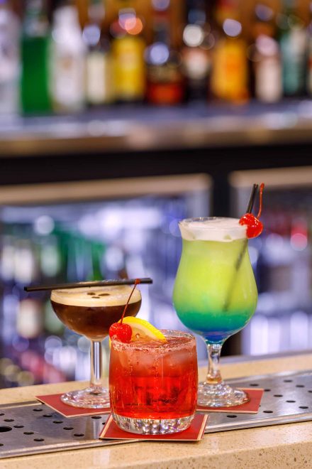 Three cocktail glasses filled with drink are kept on a bar table